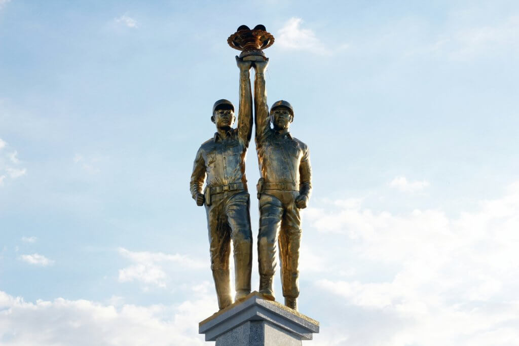 two statues stand on a pedestal holding a trophy